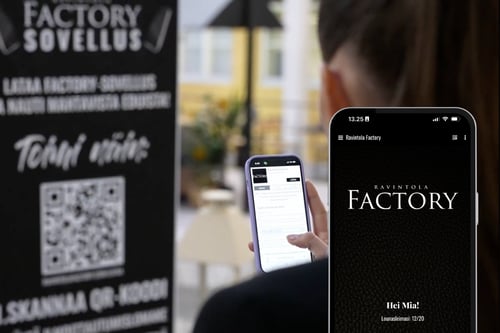 Ravintola Factoryn kanta-asiakasohjelman mainos ja QR-koodi sekä älypuhelin, jonka näytöllä näkyy digitaalinen kanta-asiakassovellus.