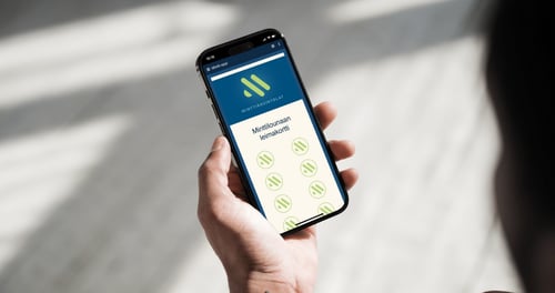 Kädessä oleva älypuhelin, jonka näytöllä näkyy digitaalinen Minttilounaan leimakortti ja vihreitä leimoja osana Minttiravintoloiden mobiilisovellusta.